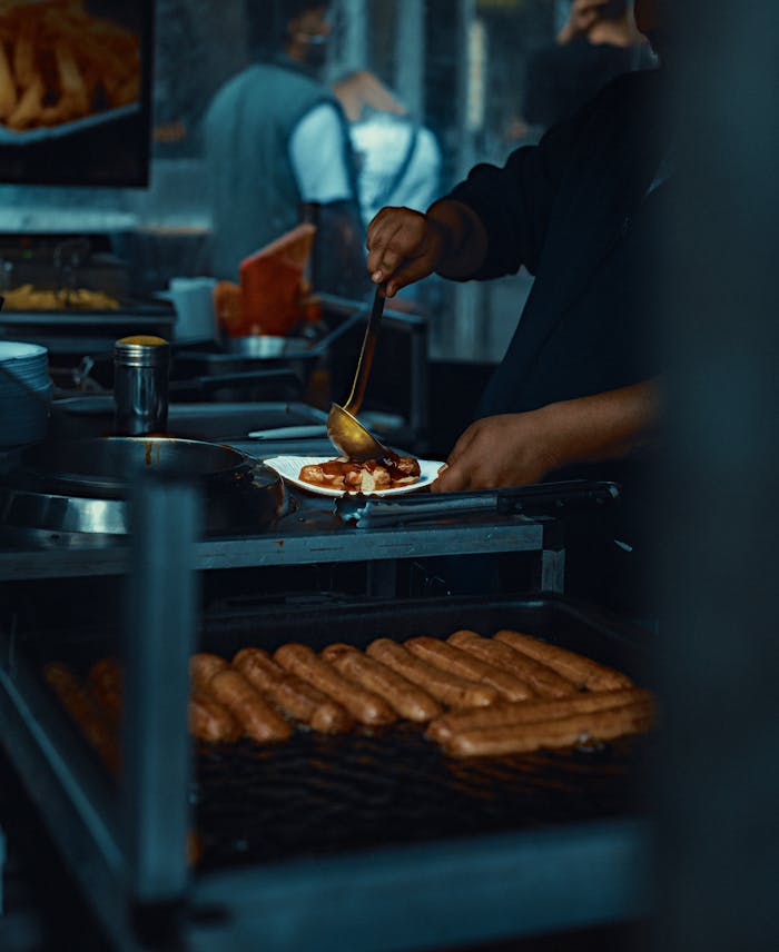 service-01 Street food vendor in Berlin pouring sauce over sausages at an outdoor stall.