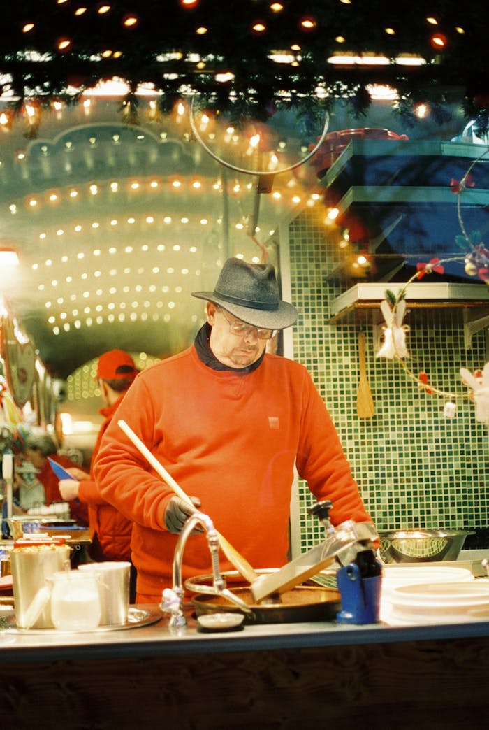 service-03 Vendor at Berlins Christmas market preparing traditional food under festive lights.