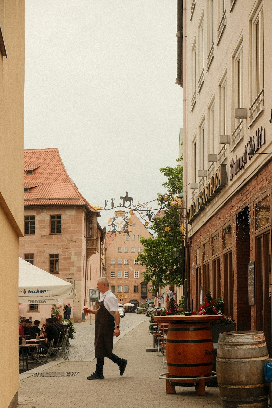 Waiter with beer walking through a quaint cobblestone alley in a historic German town with outdoor dining and charming architecture